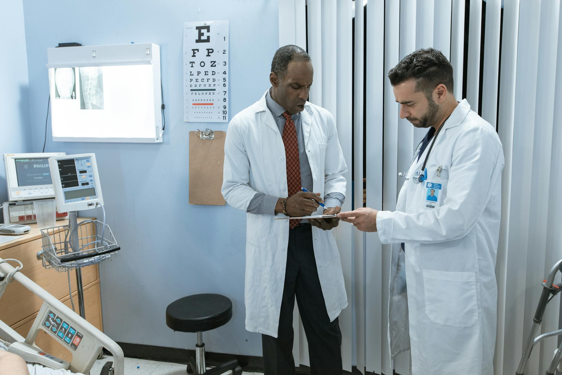 Two doctors in lab coats discussing a patient's medical chart in a hospital setting.