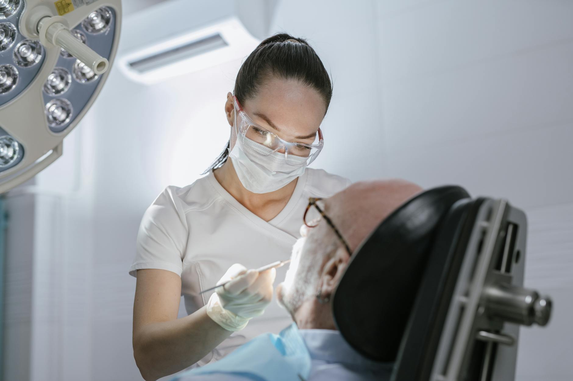 A dental professional attending to an elderly patient in a clinic setting.