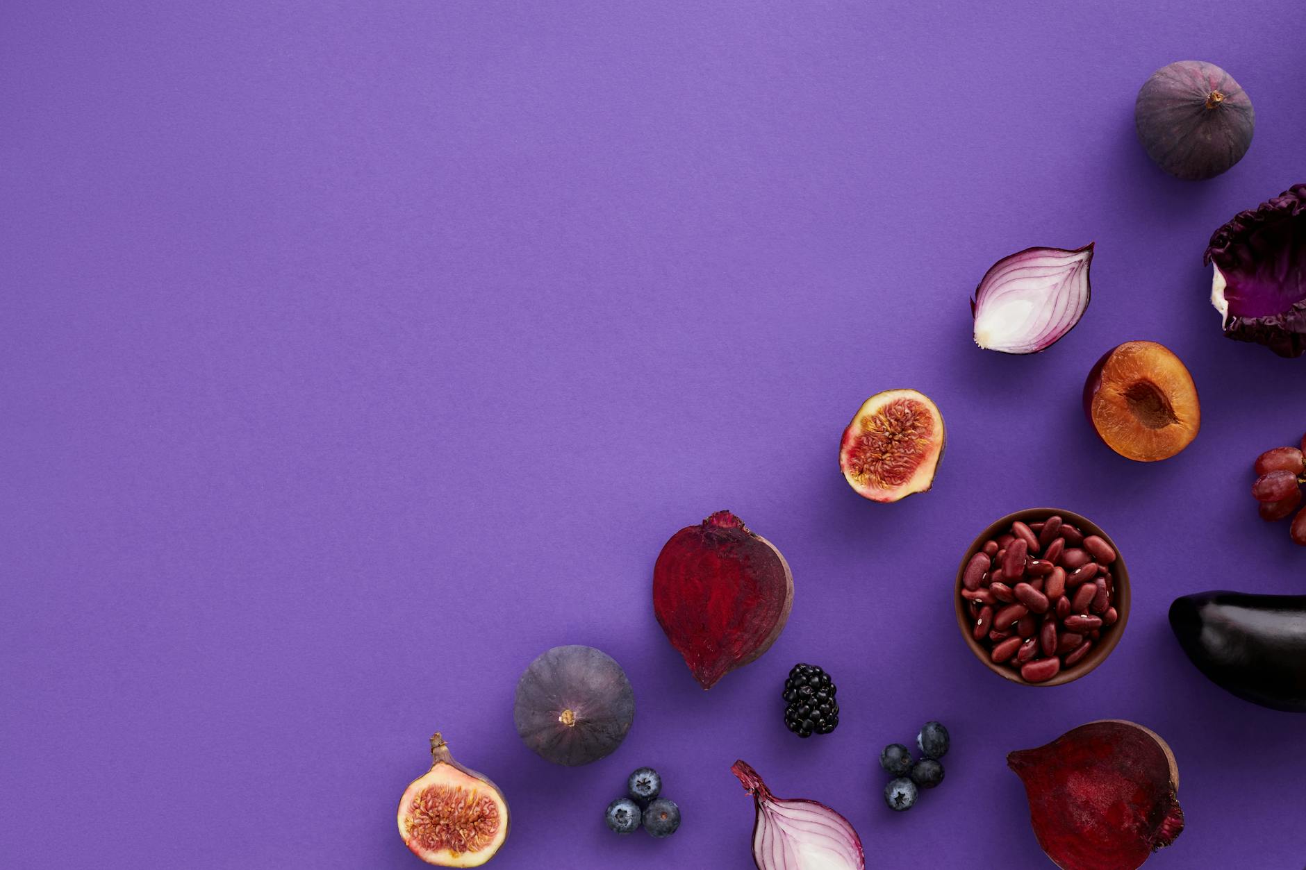 A vibrant arrangement of fruits and vegetables on a purple backdrop, perfect for health and nutrition themes.