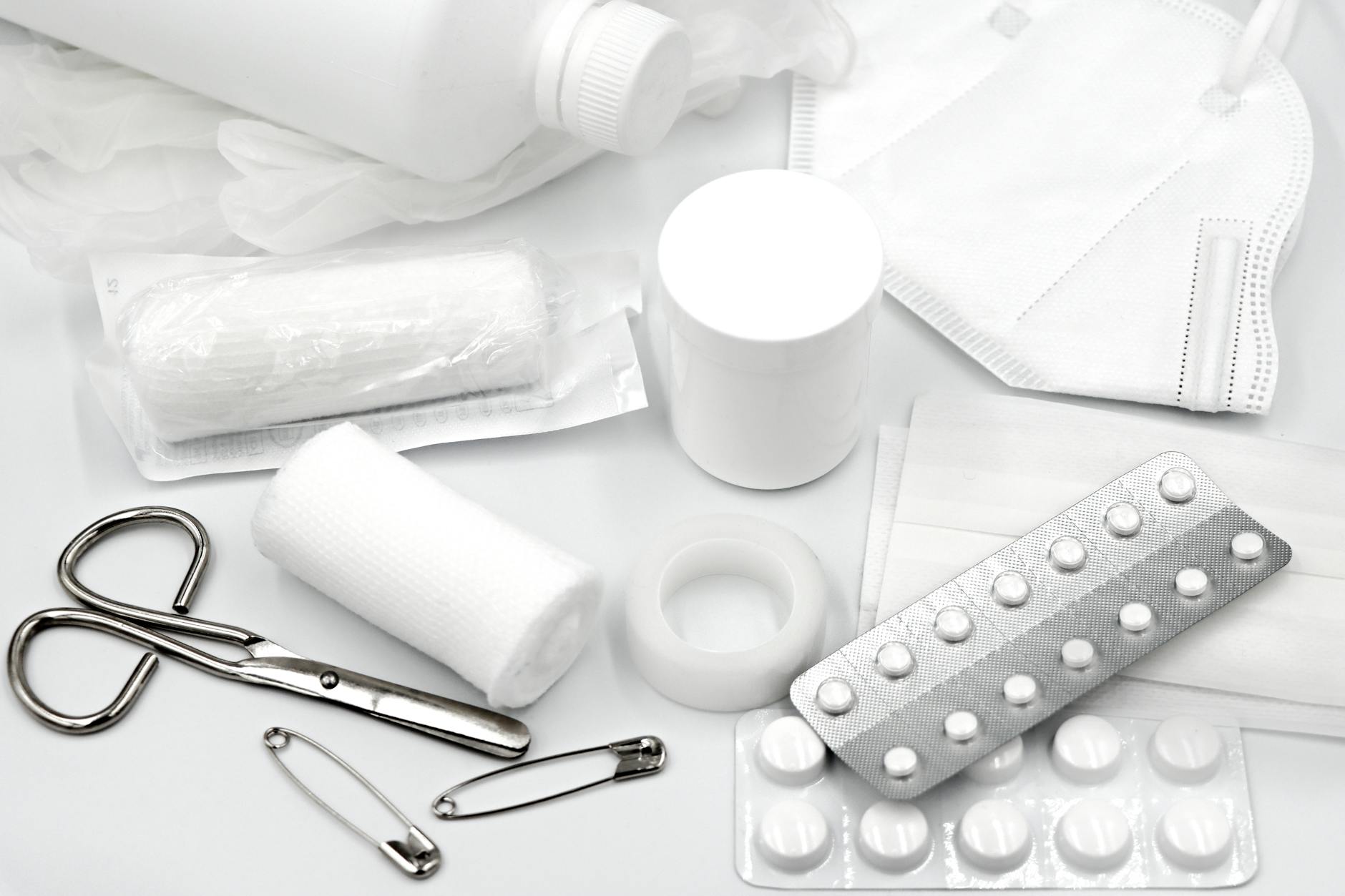 A flat lay of essential first aid supplies and medical equipment on a white background.