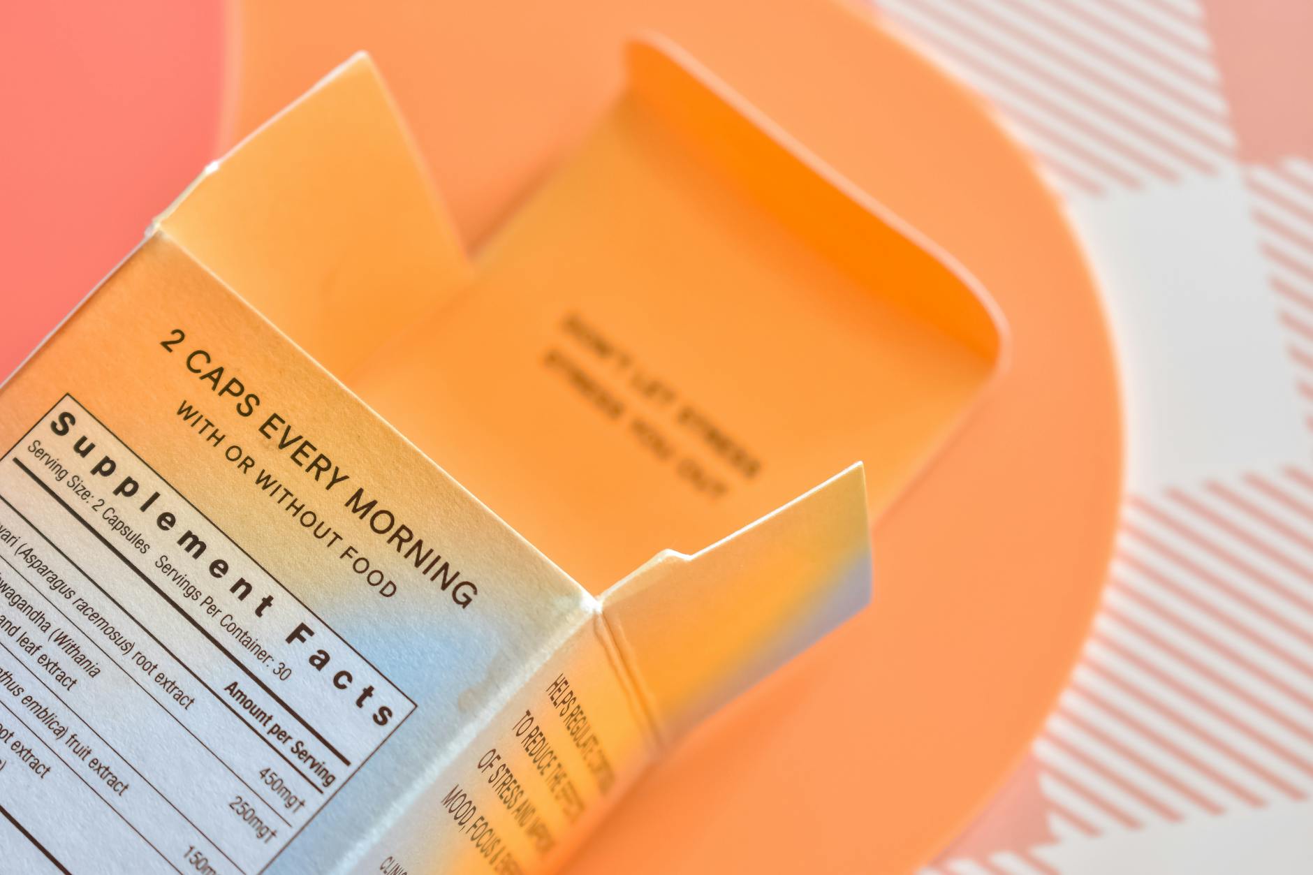 High angle view of an open supplement box on a peach-themed surface