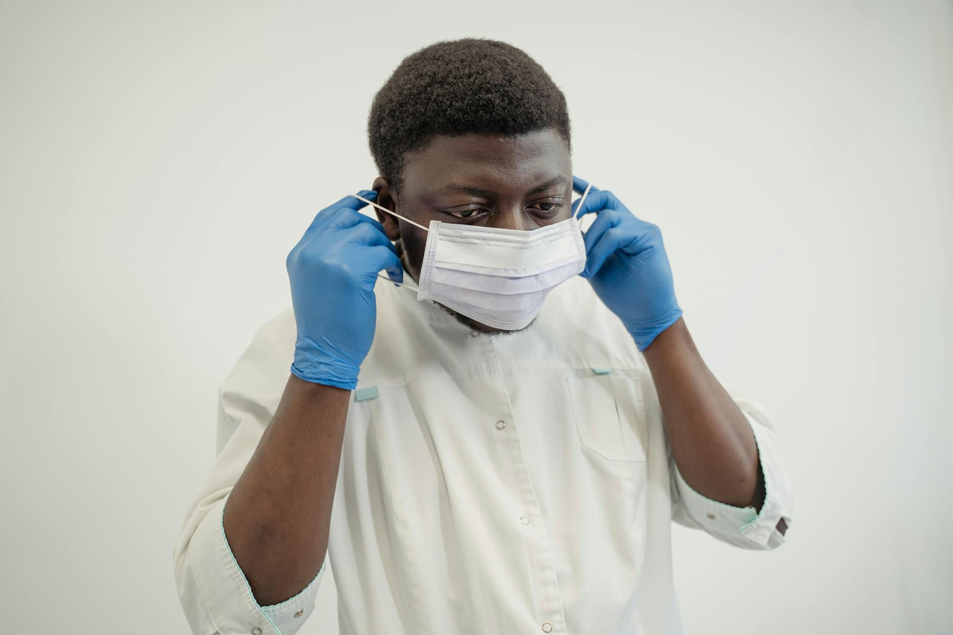 Healthcare worker wearing gloves and a mask in a clinical setting.
