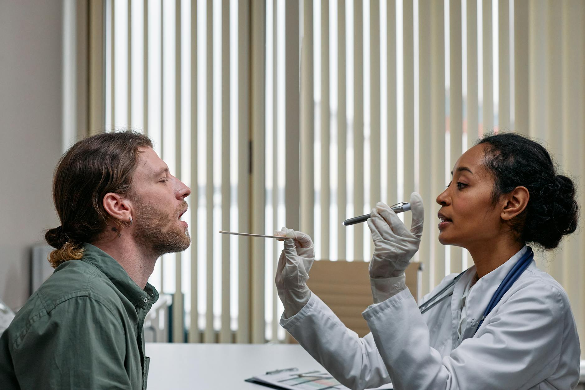 A doctor examining a patient's throat in a clinical setting, highlighting professional healthcare.